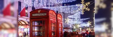 Red telephone box in London at night with Christmas lights