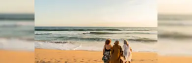Three women on the beach facing out to the sea