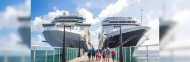 Two cruise ships at a dock, people walking towards them to board