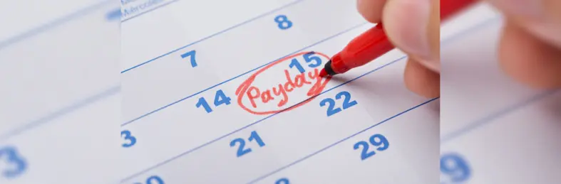 A calendar with someone circling the 15th of the month and writing 'Payday' in red marker pen.