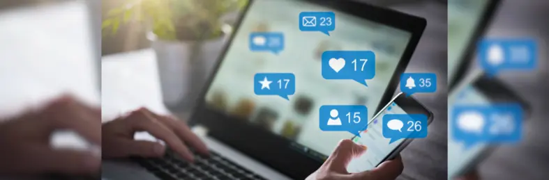 Someone working at their laptop seeing multiple notifications on their phone.