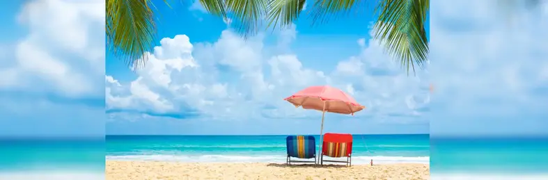 Two deck chairs on a beach.