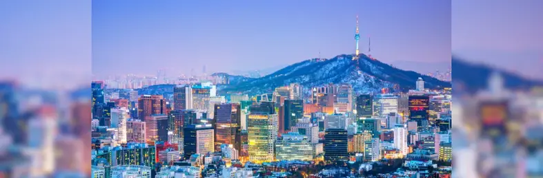The Seoul skyline at sunset against a blue/purple sky.