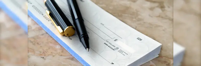A ballpoint pen resting on top of a chequebook.