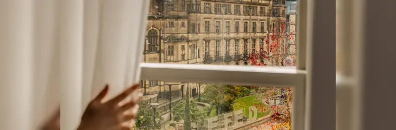 A blurred hand opening a white curtain at Radisson Blu Hotel, Sheffield.