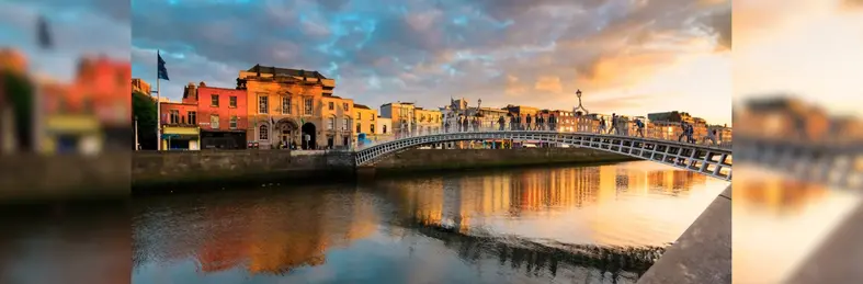 The Ha'penny Bridge in Dublin, Ireland at sunset from the bank of the River Liffey.