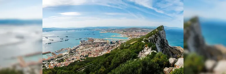 Gibraltar Rock view from above, on the left Gibraltar town and bay, La Linea town in Spain at the far end, Mediterranean Sea on the right.