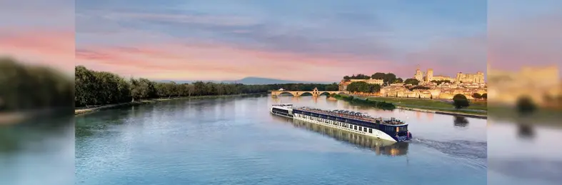 AmaKristina sailing in Avignon, France against an orange and purple sky at sunset.