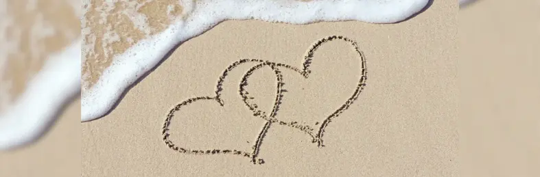 Two hearts drawn in the sand on a beach.