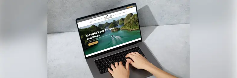 A pair of hands navigating the Elite Travel Group website on an Apple laptop.