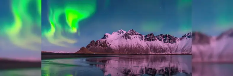 Image of the Northern Lights over snowy mountains and a lake in Iceland