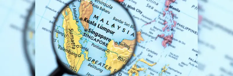 A magnifying glass focused on Singapore on a world map.