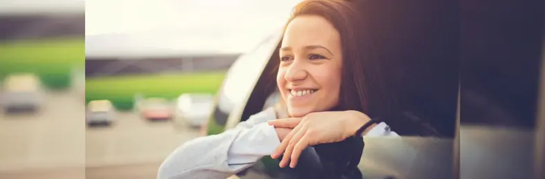 A person resting on their car window looking out.
