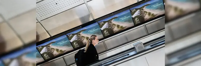 A lady on the escalator in front of the campaign ads in the background 
