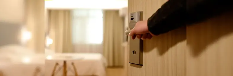 Image of a hotel worker opening a hotel door into a room