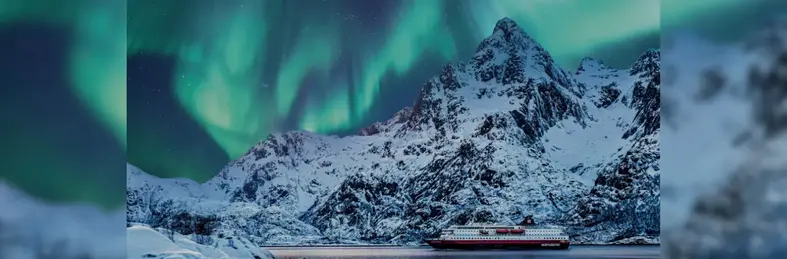 Image of a Hurtigruten ship against the backdrop of a snowy mountain and the Northern Lights