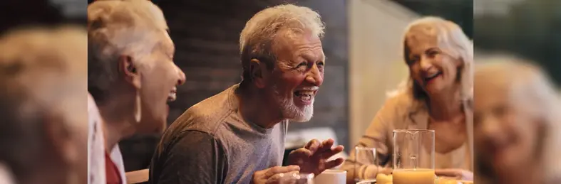 Three guests laughing around a dinner table on a Jules Verne Sociably Solo tour. 