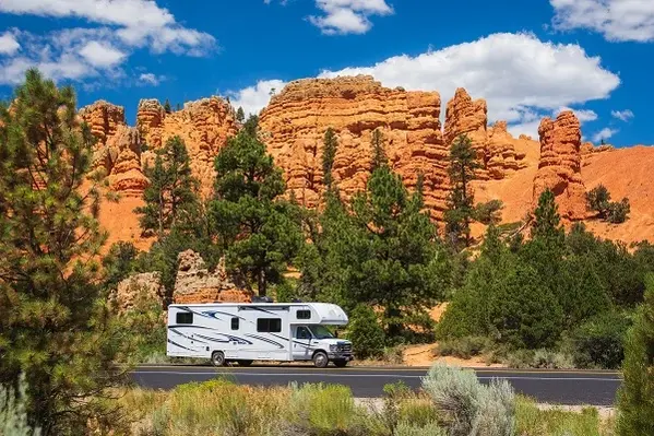 White RV travels on a tarred road through red rock country