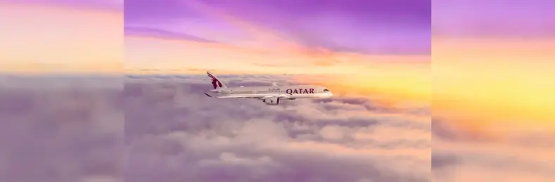 Image of a Qatar Airways plane flying through a yellow and lavender sky