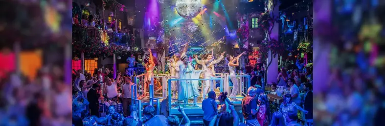 The end number at Mamma Mia! The Party with the singers and dancers on stage surrounded by guests dancing