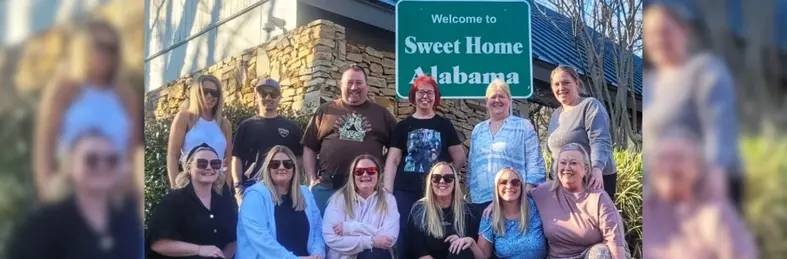 Travel agents posing in front of a 'Welcome to Sweet Home Alabama' road sign on a Newmarket Holidays fam trip in Alabama, USA.