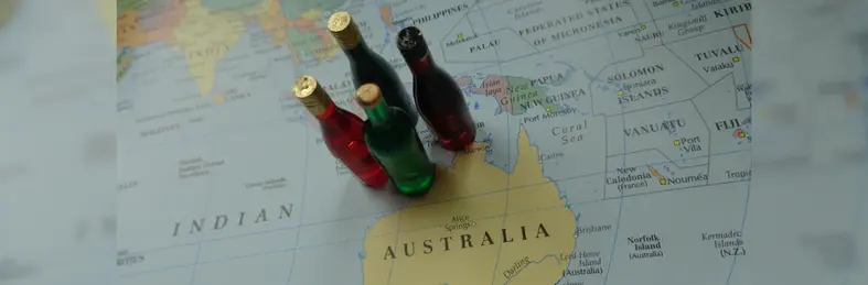 A map of Australia with three miniature bottles of wine resting on top.