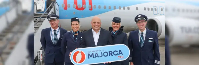 TUI cabin crew holding a large boarding pass to Majorca