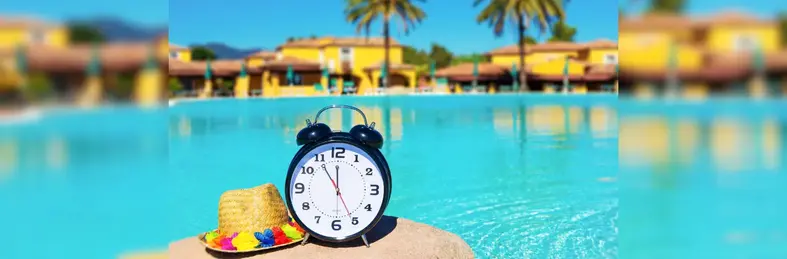 A clock next to a sun hat and swimming pool
