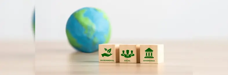 A globe of the earth next to three wooden blocks labelled Environmental, Social and Governance. 
