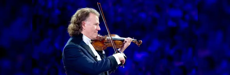 André Rieu playing violin on stage.