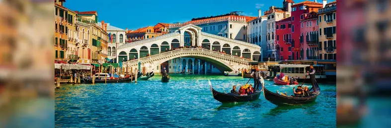 Gondolas sailing past Ponte di Rialto on Venice's Grand Canal.
