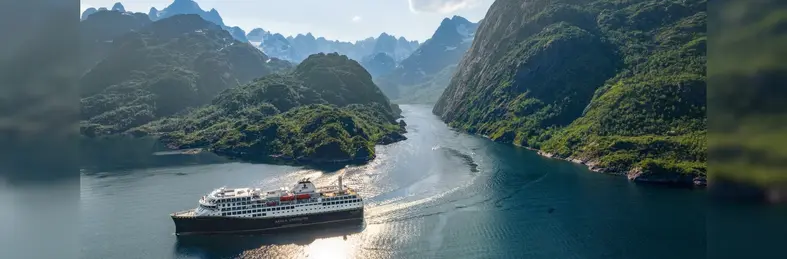 A Havila Voyages ship sailing through a Norwegian fjord. 
