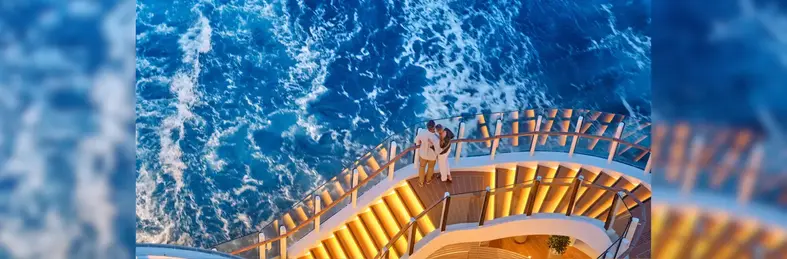 Couple huddled together on a lit stairway looking into the sea