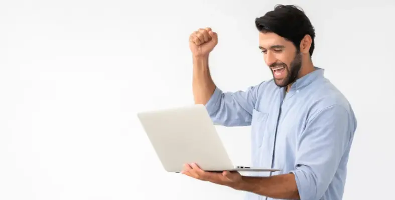 A person celebrating whilst holding their laptop open.