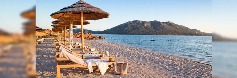 Sun loungers laid out in a row on a beach in Corsica.