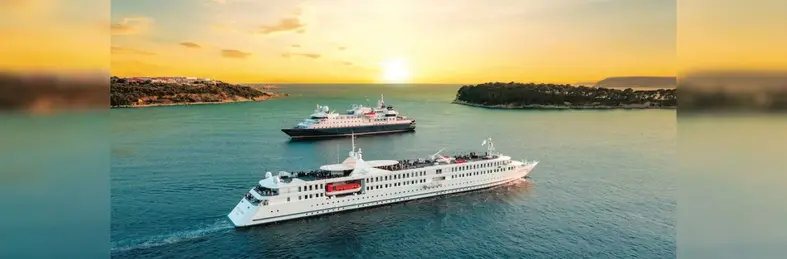 Two CroisiEurope cruise ships, the MS La Belle des Océans and the MS La Belle de l'Adriatique, at sea near sunset.