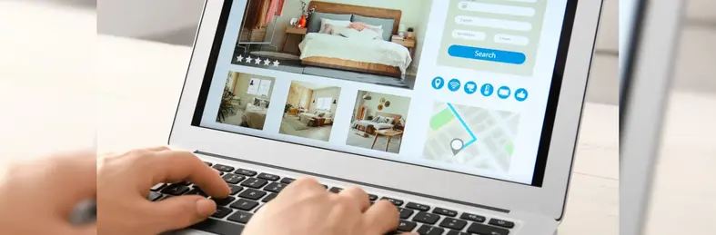 A person booking a hotel on an Apple Macbook laptop.