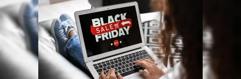 A person sat on a sofa browsing a Black Friday sale on an Apple Macbook.