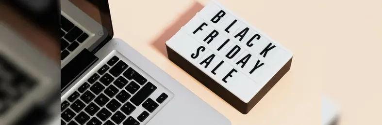 A lightbox with the words 'Black Friday Sale' on it next to an Apple Macbook laptop.