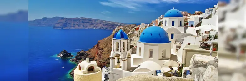 The iconic cliffside architecture and blue-domed churches of Santorini, Greece, overlooking the volcanic caldera and the Aegean Sea. 