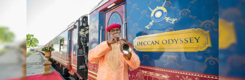 Man with a trumpet in front of the Deccan Odyssey train