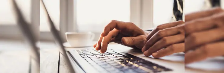 Man's hands typing on a laptop