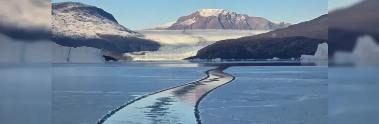 Ship tracks in the sea ice leading away from a Greenland glacier