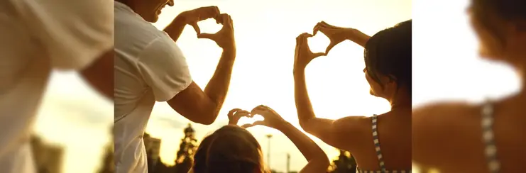 Mum, dad and child doing heart hand signs