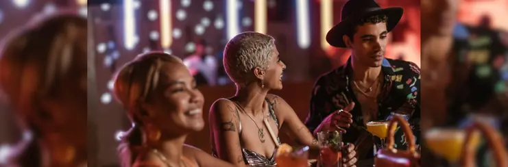 Two women and a man at a bar smiling