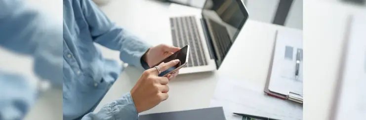 A man on his phone, next to a laptop