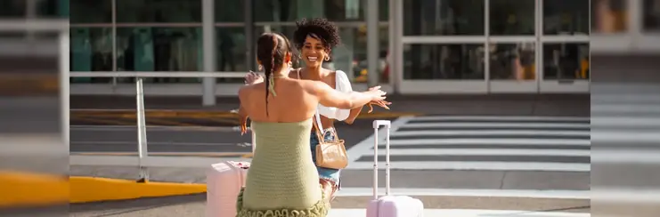 two women embracing outside an airport