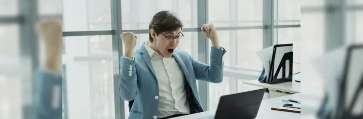 A man celebrating in front of his computer