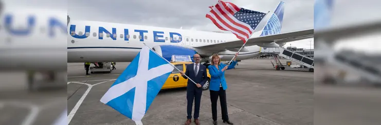 A man and a woman holding a Scottish and a USA flag respectively outside of a United Airlines aircraft