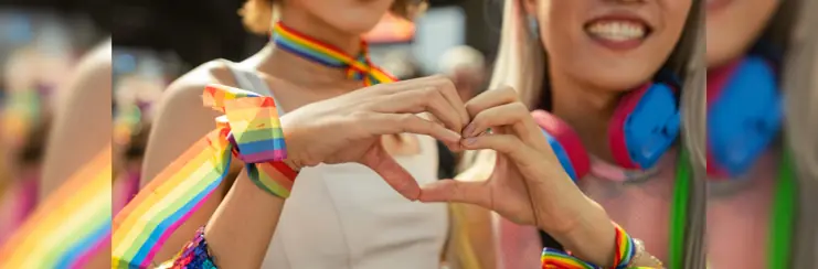 Two women making a heart at a pride parade 